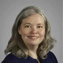 Staff member with shoulder length blonde and silver wavy hair wearing a navy blue top